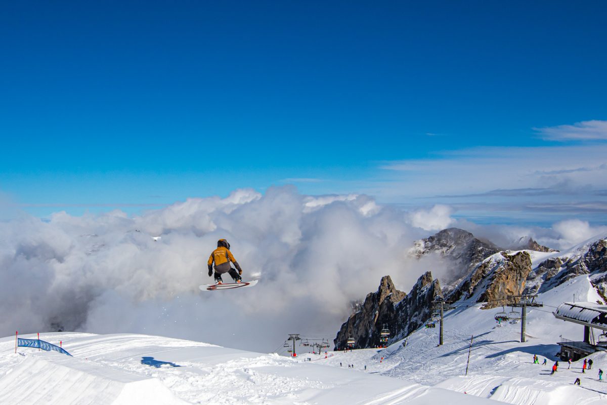 Surfeur au dessus d'une bosse sur fond de nuage sur le SnowPark de Cotch à Gourette