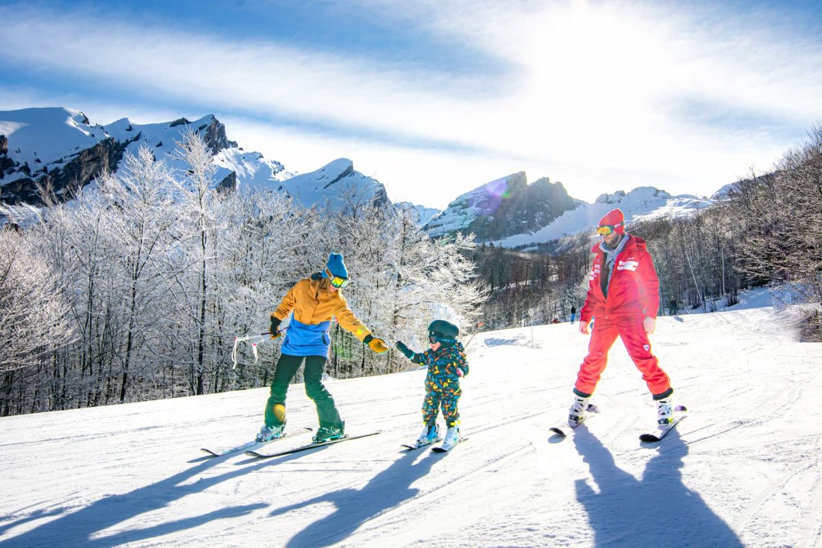 Une maman et son enfant descendant la piste bleu du Bois noir à Gourette accompagnés d'un moniteur de ski de l'ESF