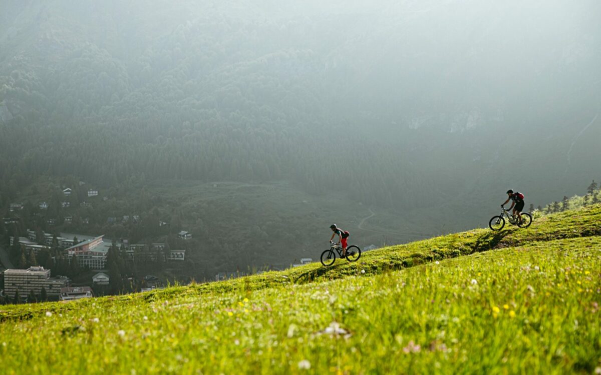 Deux pratiquants de VTT de montagne descendent tranquillement, debout sur les pédales au petit matin sur la station de Gourette en Vallée d'Ossau dans les Pyrénées.